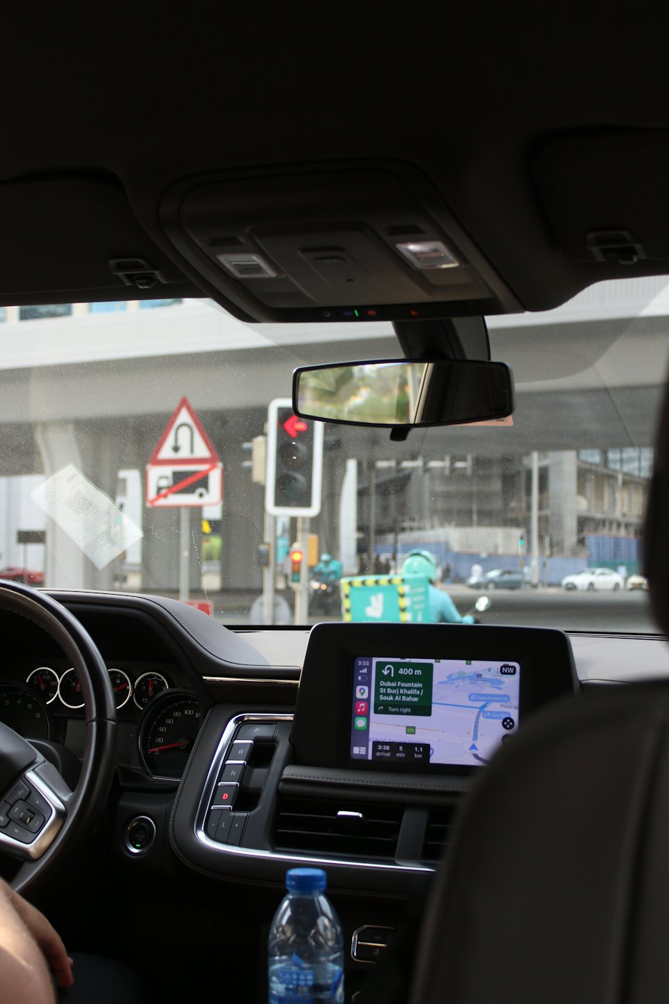 Driver views city street through car windshield with navigation map.