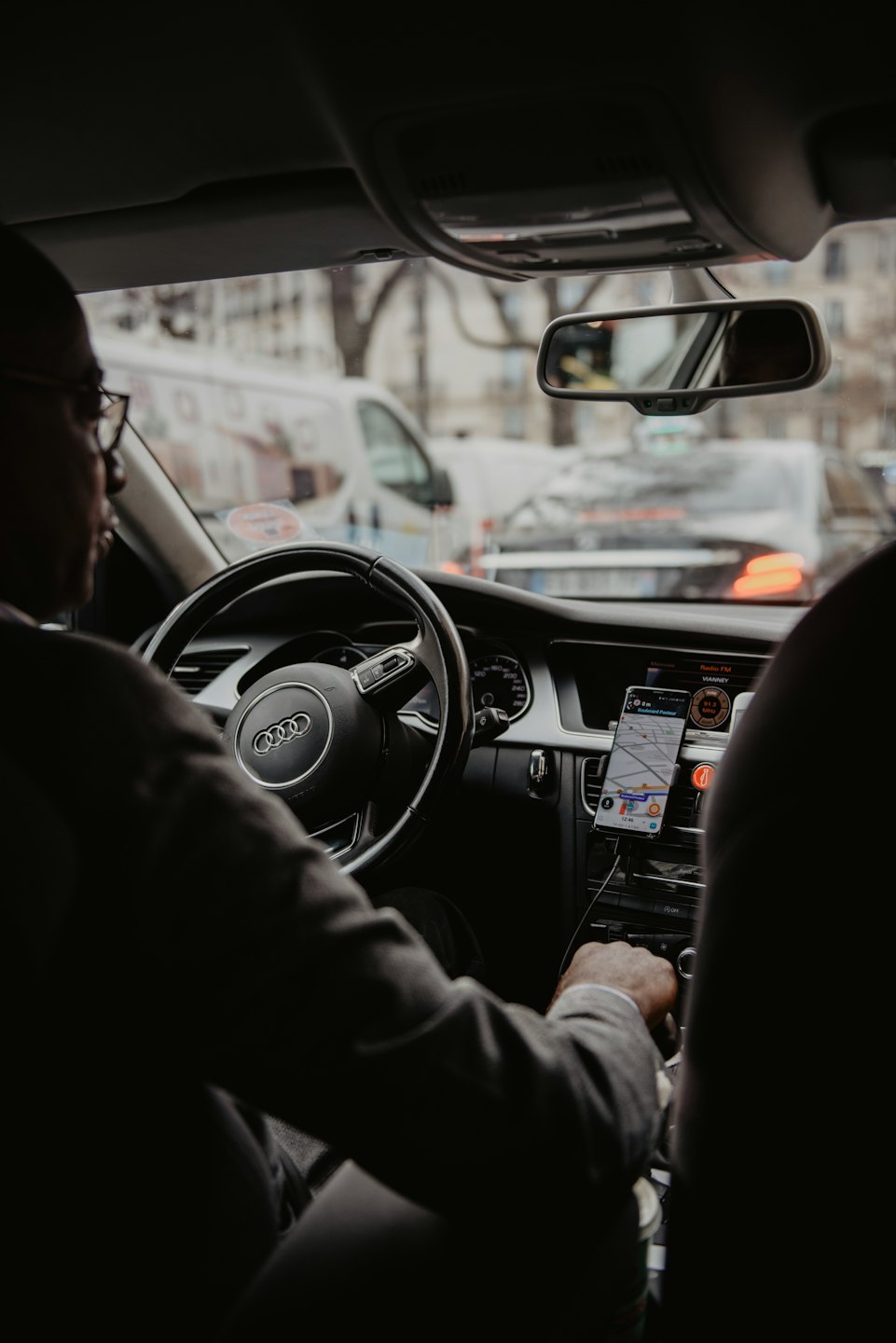 Driver's hands on steering wheel navigating city traffic.